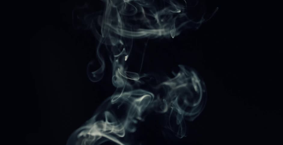 Close up of wisps of white smoke floating up against a black background