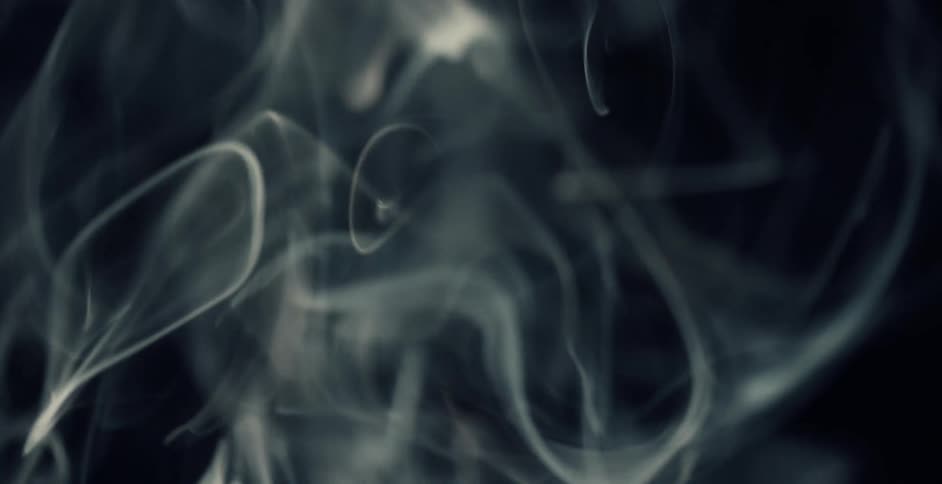 Light illuminates wisps of smoke floating in the darkness