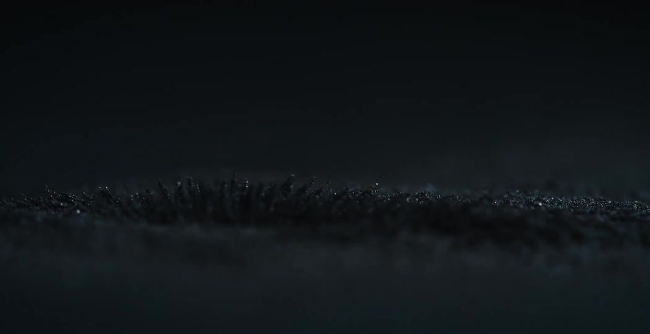 Iron dust on a dark room rises over the surface when a magnet moves underneath