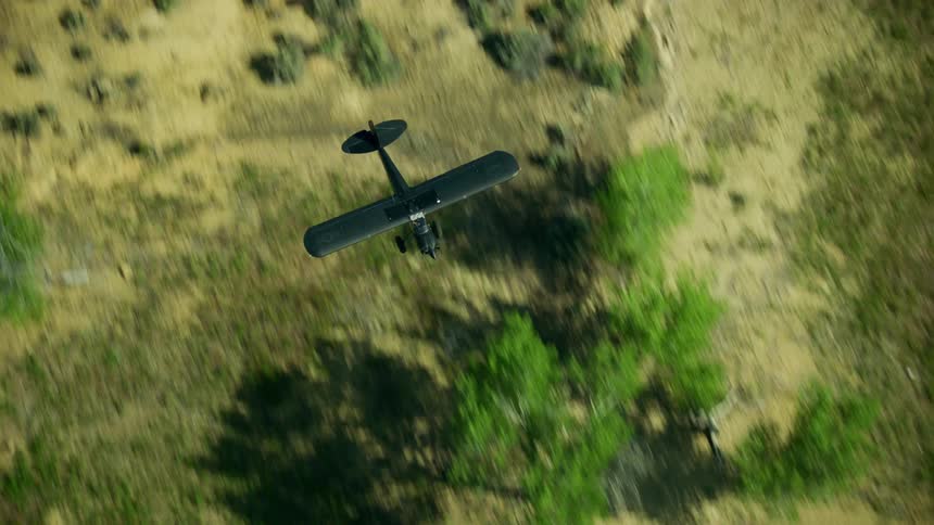Looking straight down on a propeller plane flying over scrub bush and a reservoir lake