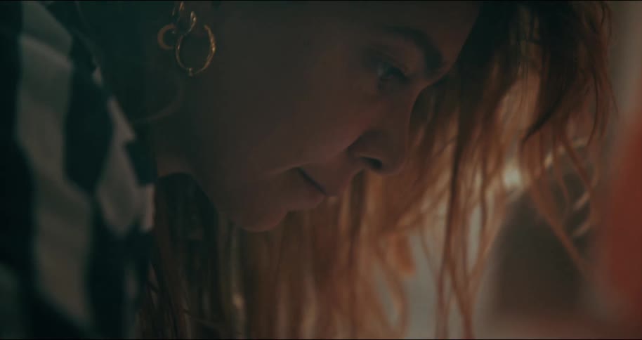 A womans hair cascades around her face while she looks down