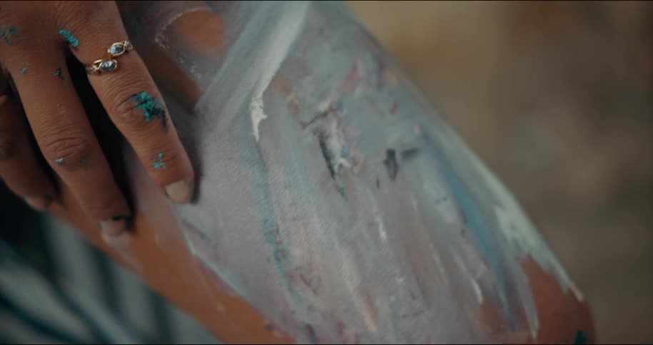 Woman with two rings on her fingers touches paint covered skin