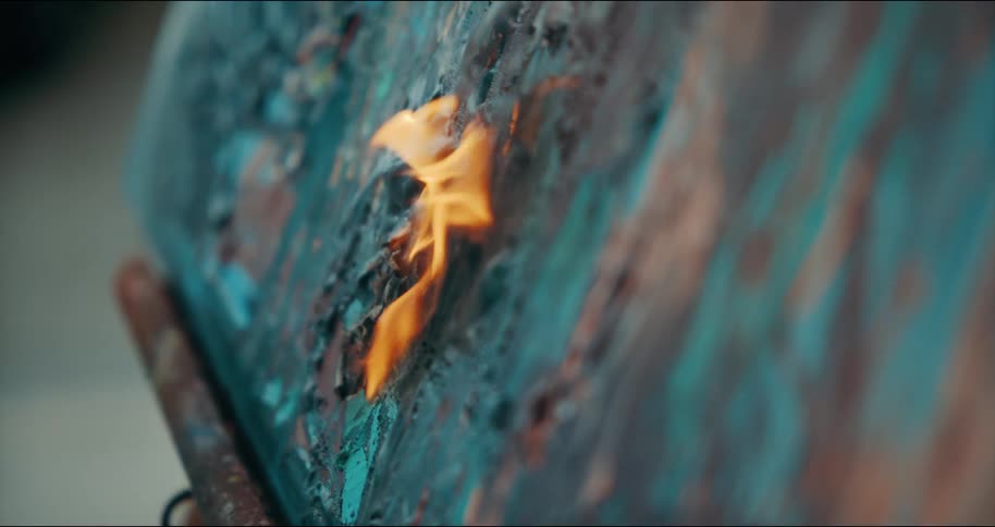 An artist uses an air gun to out the flames on her canvas