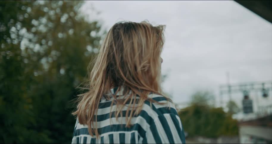 A woman is standing outside next to a road looking around