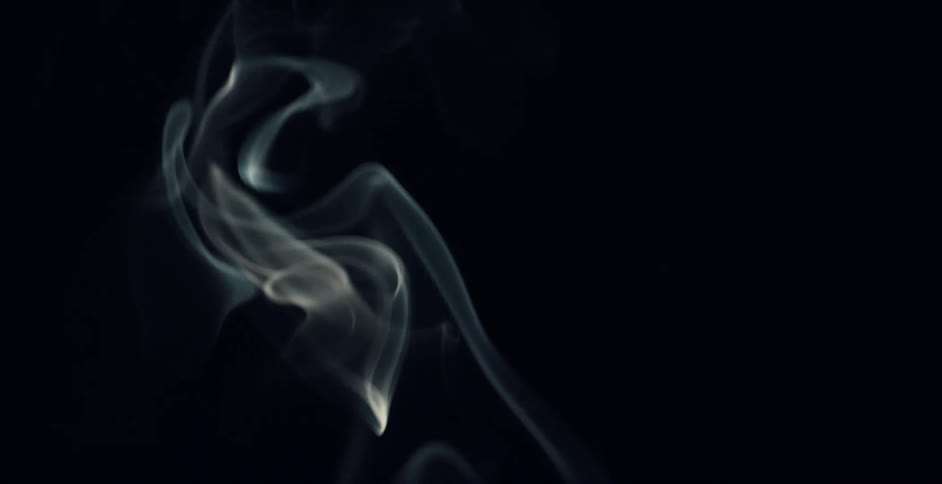 Light illuminates wisps of smoke floating in the darkness