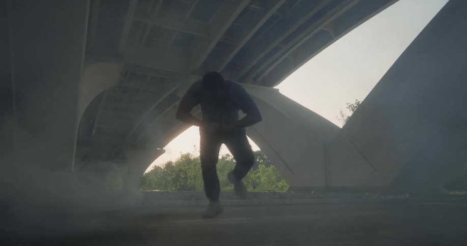 A man is under a bridge doing creative moves