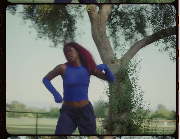 Female dancer moves through dance steps standing in park