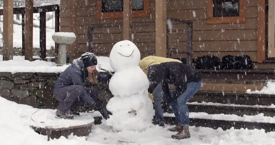 Three people build a snowman