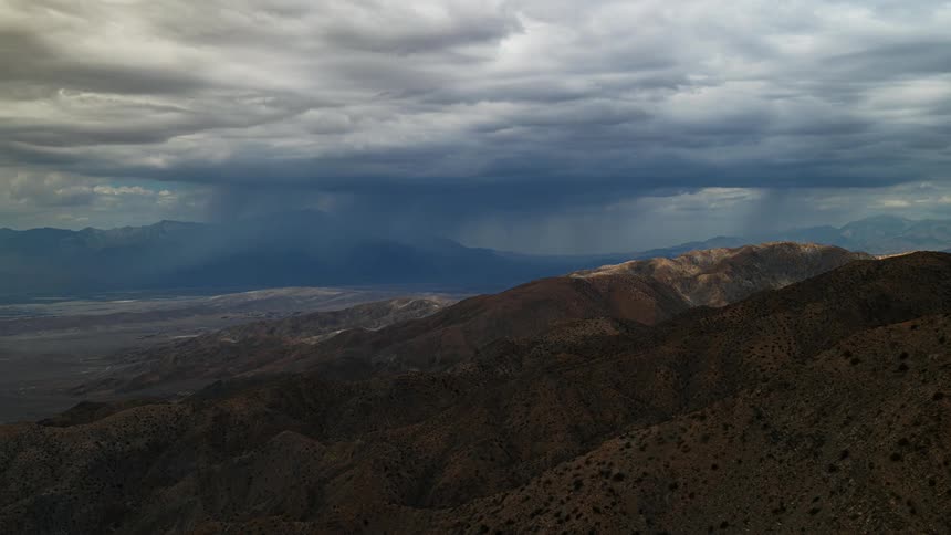 The sky is full of clouds that pass over an expansive mountain range