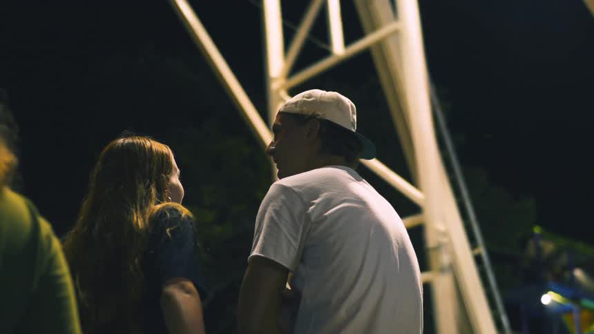 Couple stand talking while waiting for carnival ride