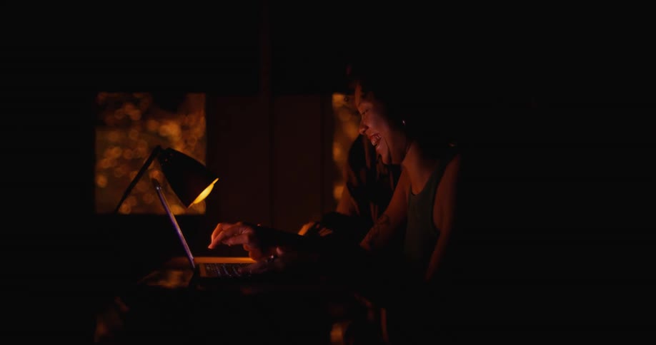 Two women laugh and look at a laptop