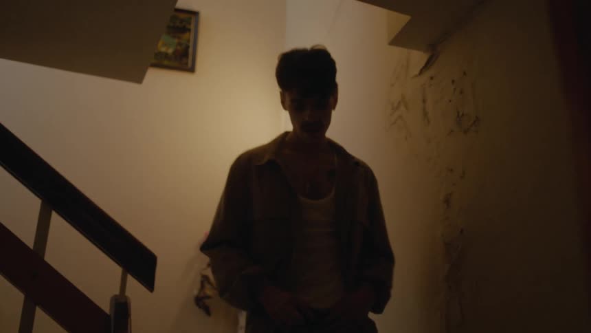 A young man hurriedly descends the stairs inside the residence that hes in