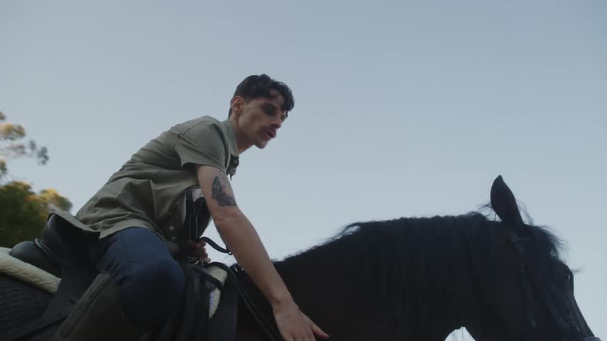 Man sitting on horse pats its neck
