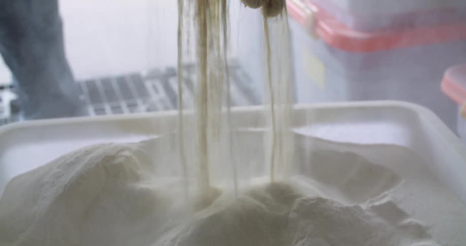 A person sifting flour in their hands