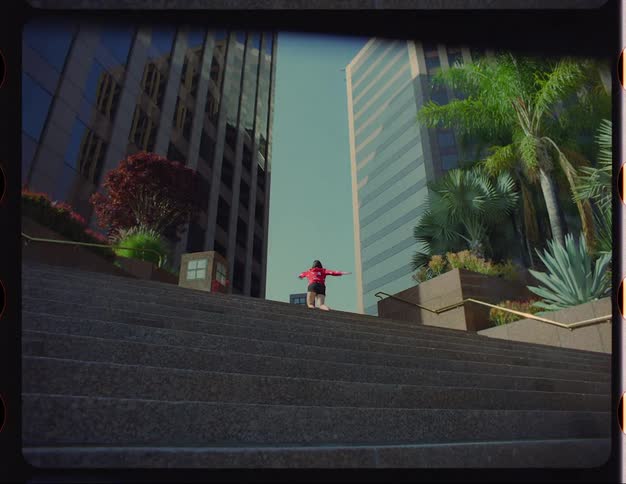 A woman dances at the top of an outdoor staircase in a metropolis during the day