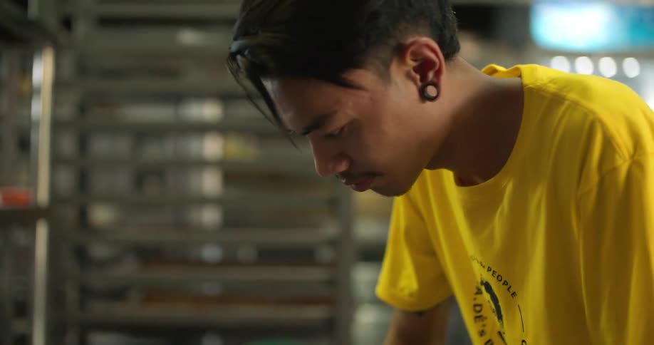 A man kneads dough on the counter in an industrial kitchen