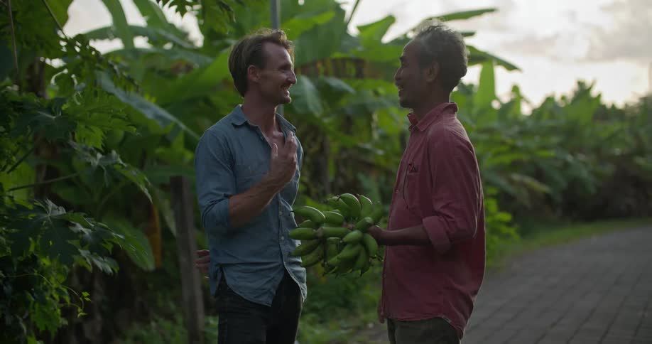 Two co workers are talking together and holding bananas