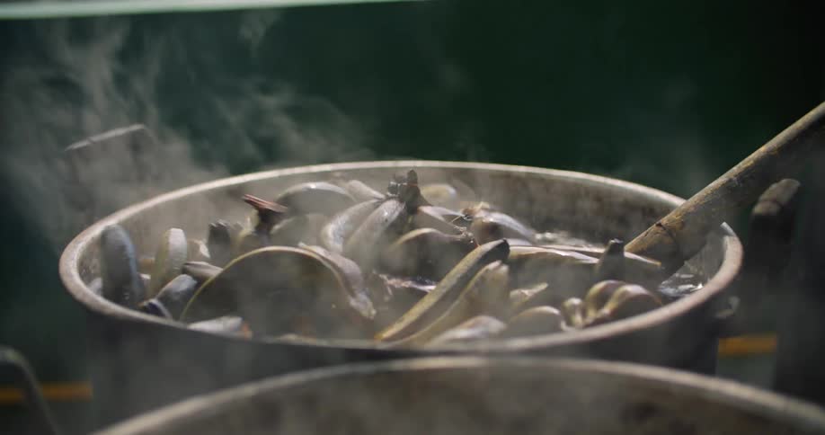A person boils unpeeled bananas in a large pot