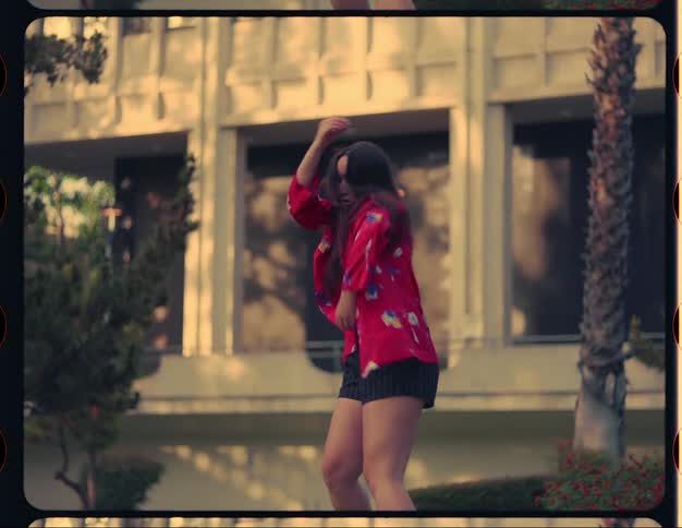 Woman dances on grass near building