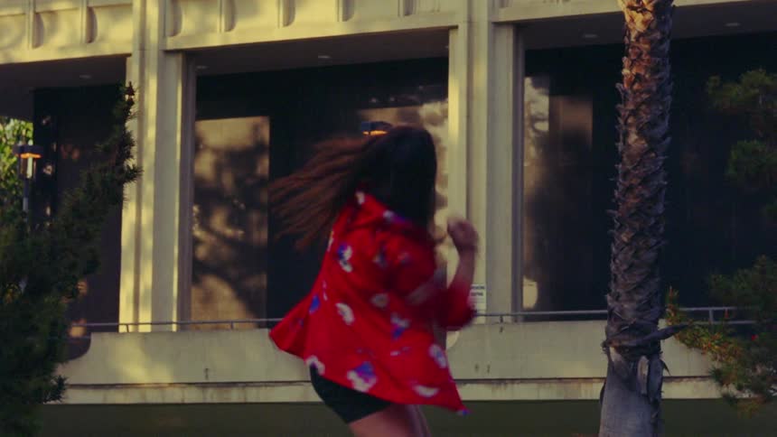 A woman is dancing outdoors in a neighborhood