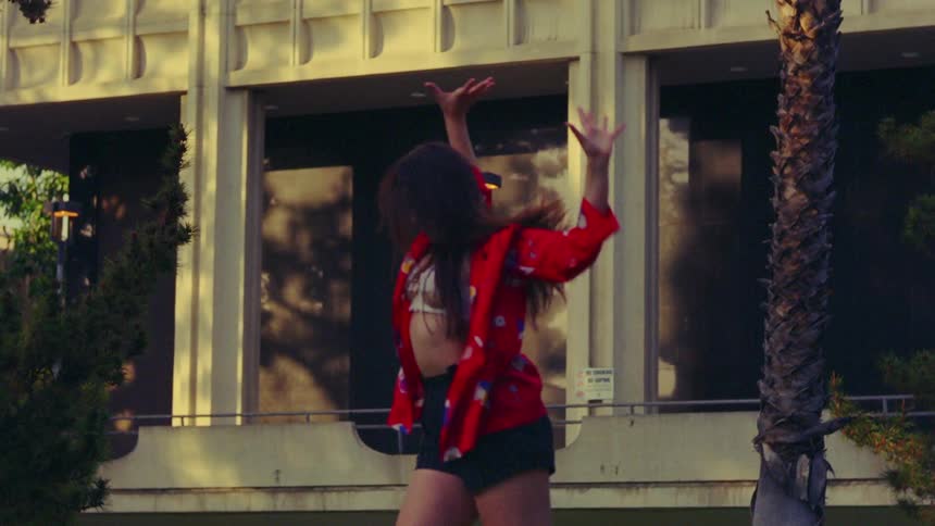 A woman dances in front of a building