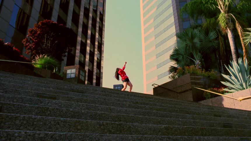 A woman is dancing on a staircase in a city