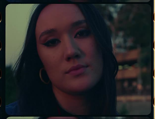 Close up of the face of a young woman wearing a colorful red jacket outdoors caught on vintage film