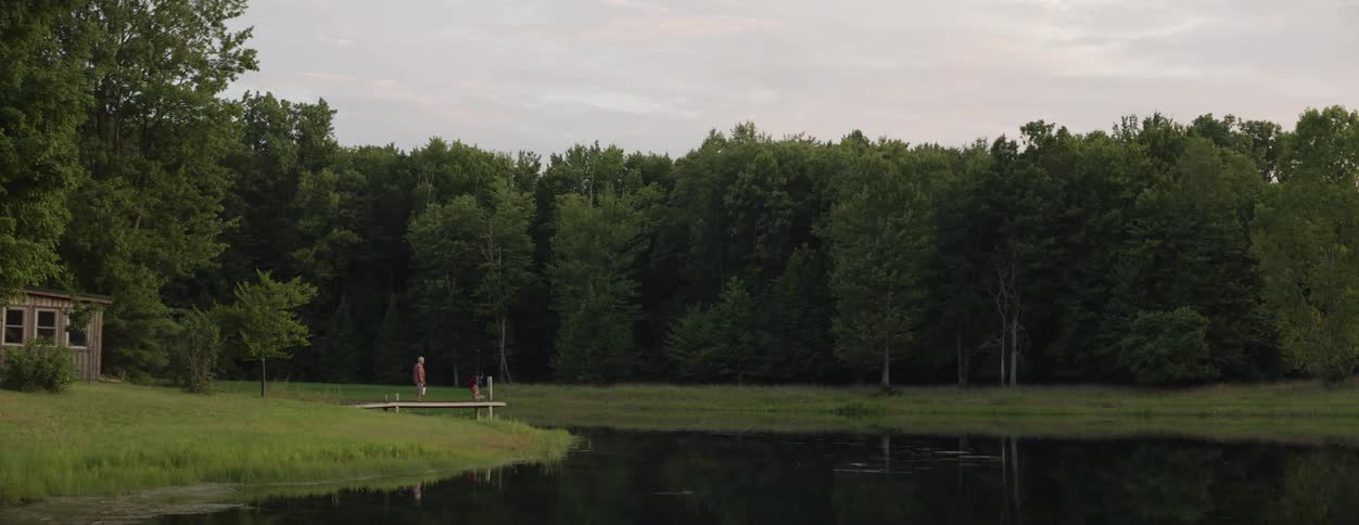 Two people walk towards the lake in the distance