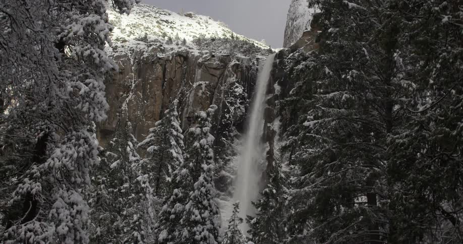 A waterfall flowing over a tall, snow-covered cliff
