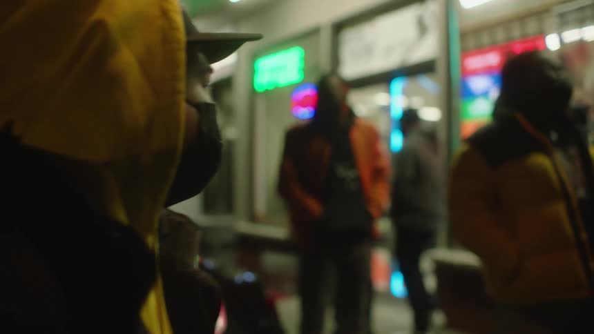 A group of guys hanging out in front of a store wearing winter jackets and masks