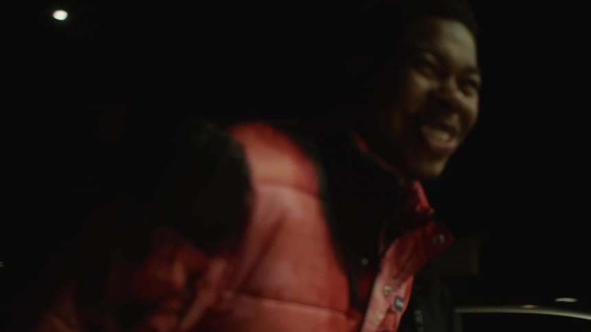 A man laughs and smiles as he walks up to his friends hanging out in front of a store