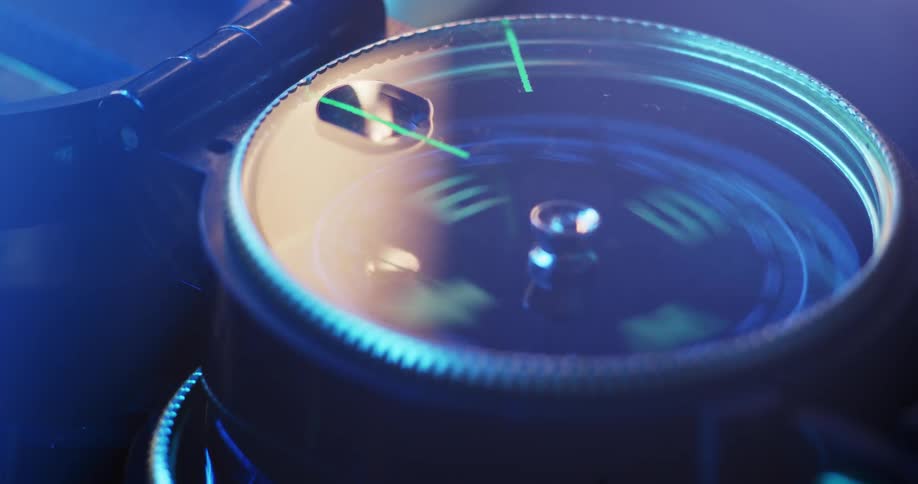 Light reflects off the glass face of a compass that is spinning and jumping