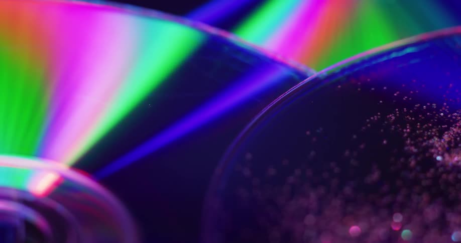 The surface of compact discs reflects rainbows of color and light