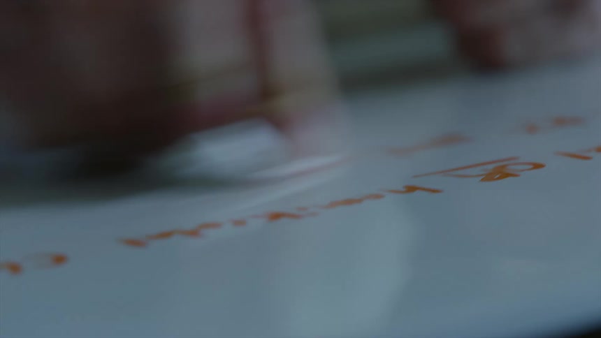 A hand is using a paper towel to wipe off red writing on a white board