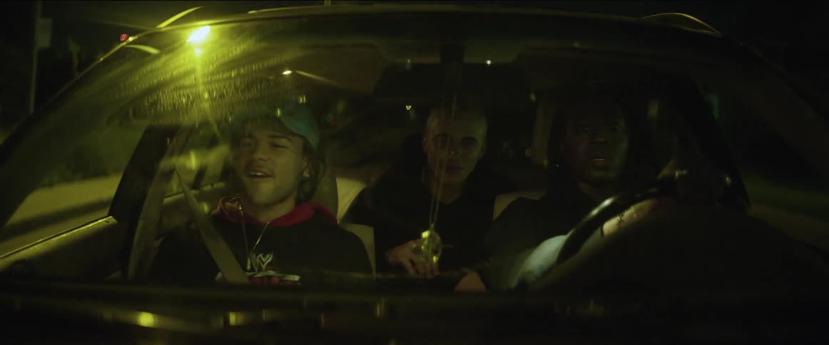 Men smile and talk while driving along street at night