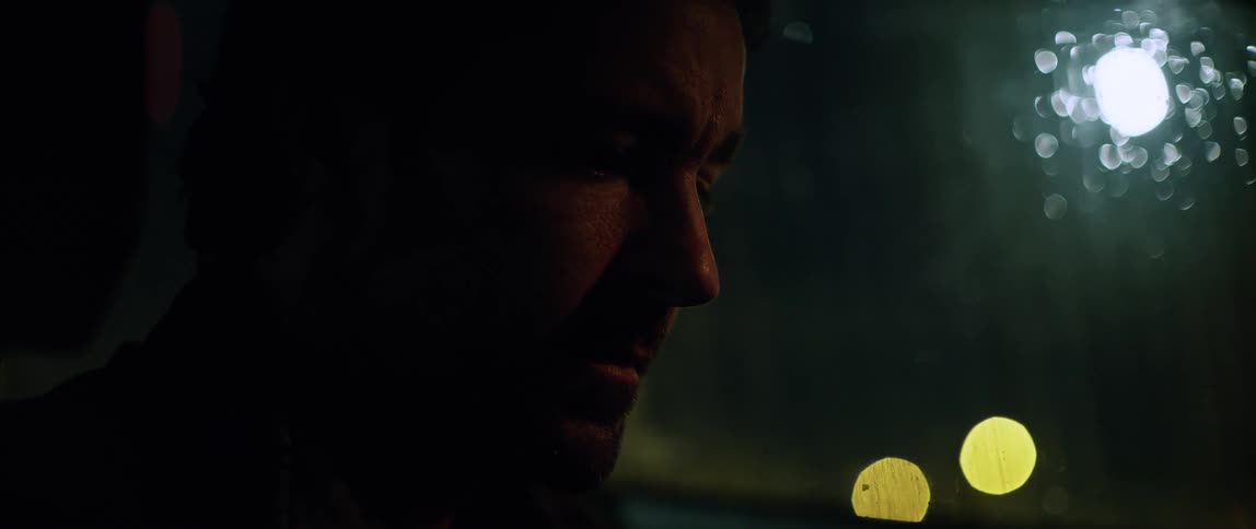 Man sits in car looking down as light glares through side window
