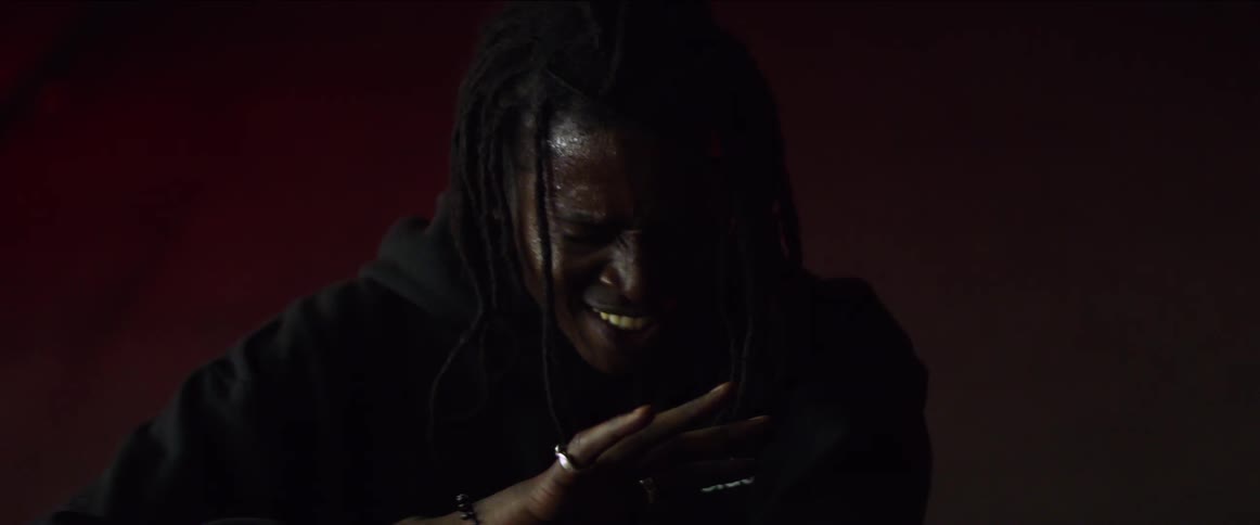 A black man with dread locks is holding his hand out as he laughs