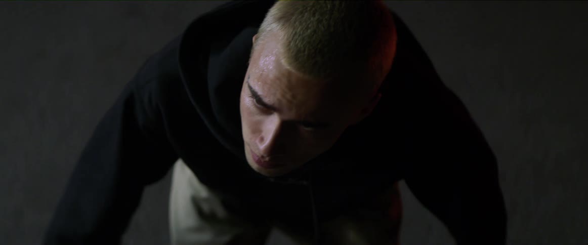 Blonde man with black hoodie and rings gets down on floor raising hands