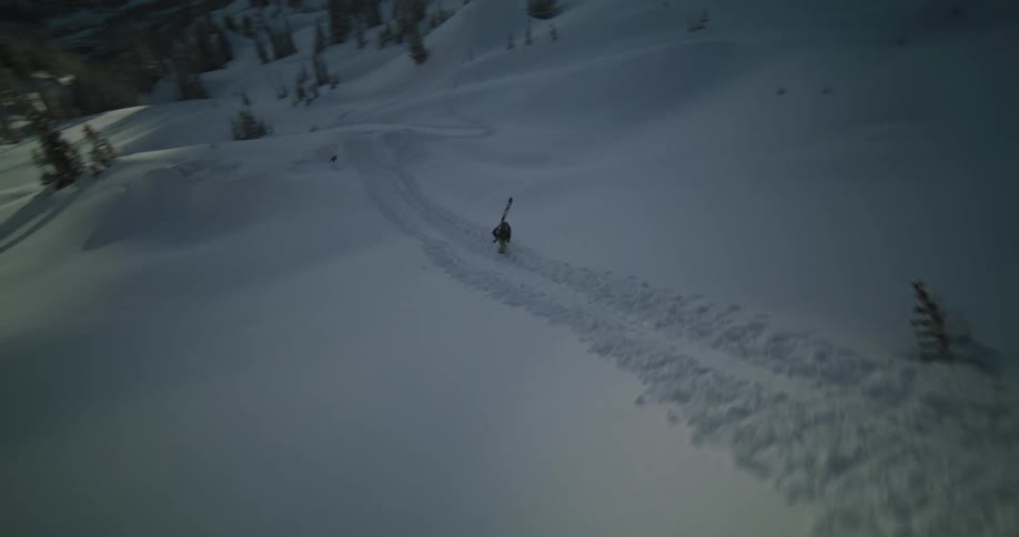 A person carries skis up a big snowy hill