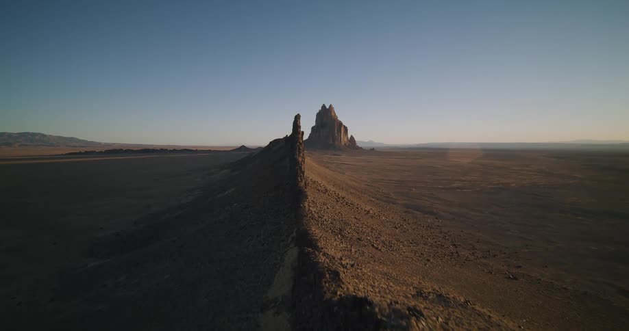 Buttes stand tall among rock formations in the desert badlands with a mesa in the distance