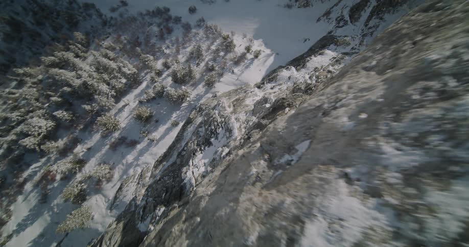 Roads run through a snow covered forested mountain valley below a steep icy slope