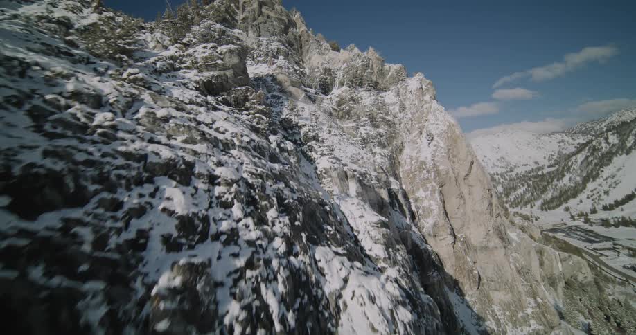 Snow dusted jagged mountain ridge and valley under a blue sky