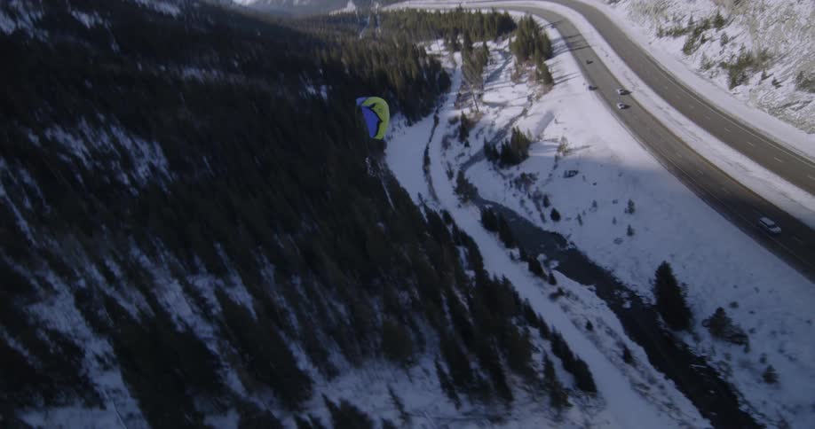 A base jumper sails through the sky landing right on target next to the car and friend waiting