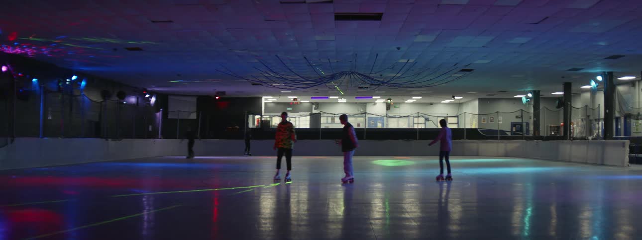 Teenagers roller skate at an indoor rink