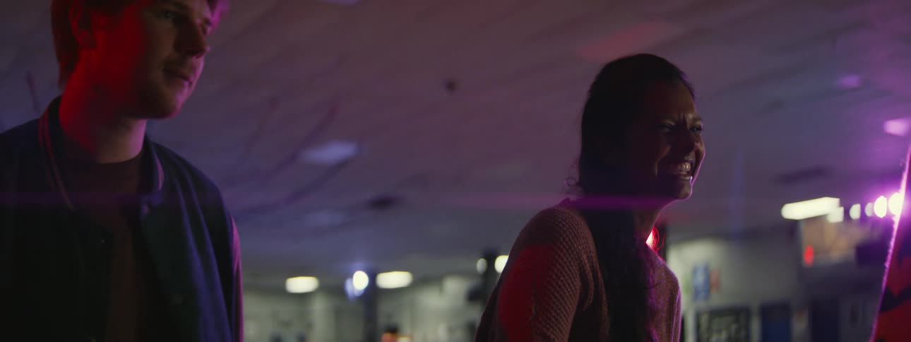 Three teenagers laugh and talk as they skate at a roller rink