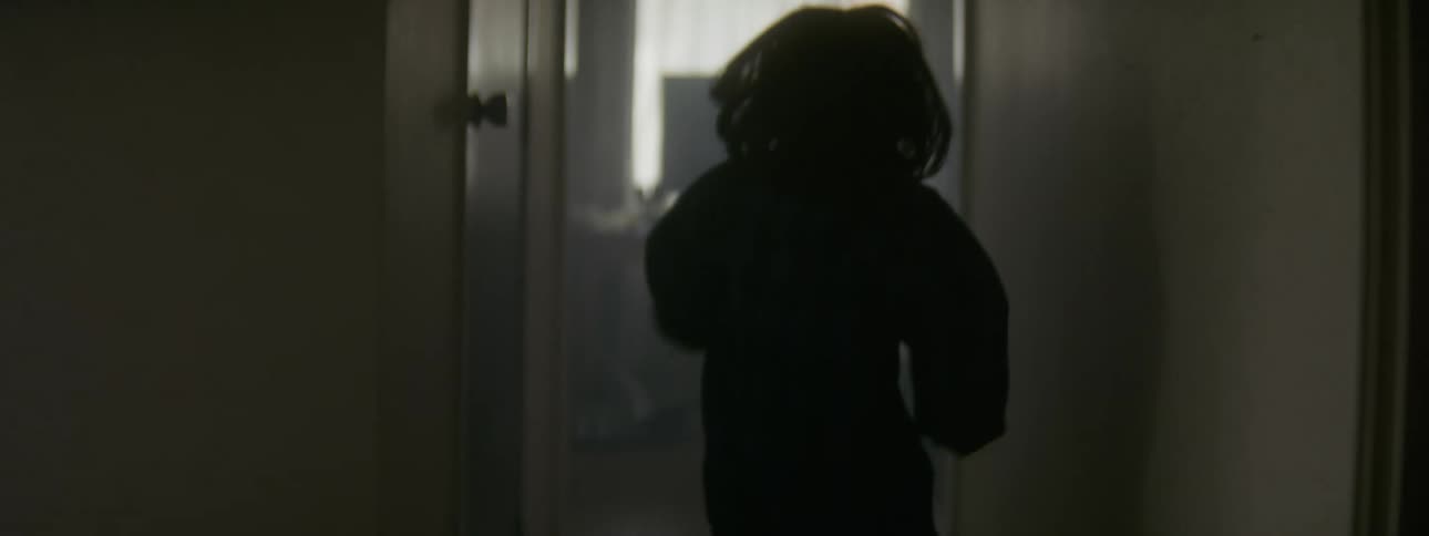 A little girl skips as she goes down a hallway