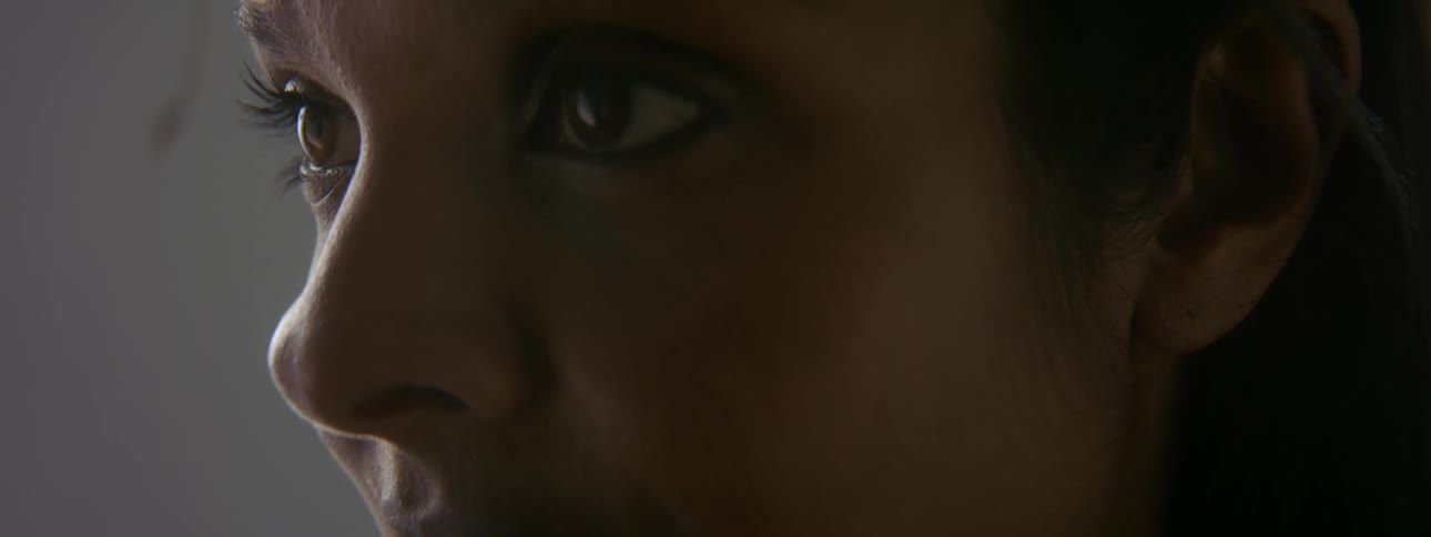 Woman with straight brown hair stands and stares