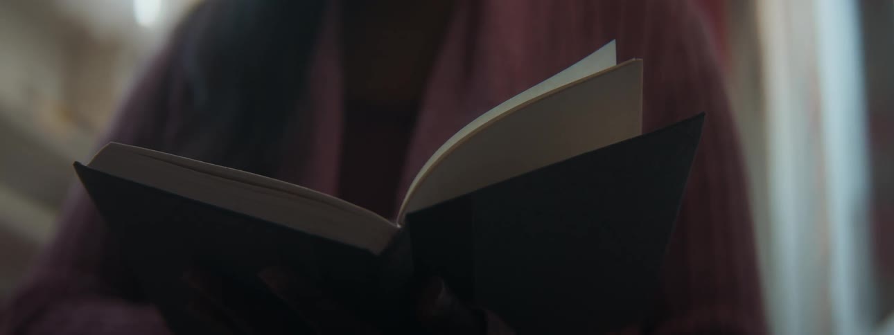 Woman with long hair stands flipping through hardback book