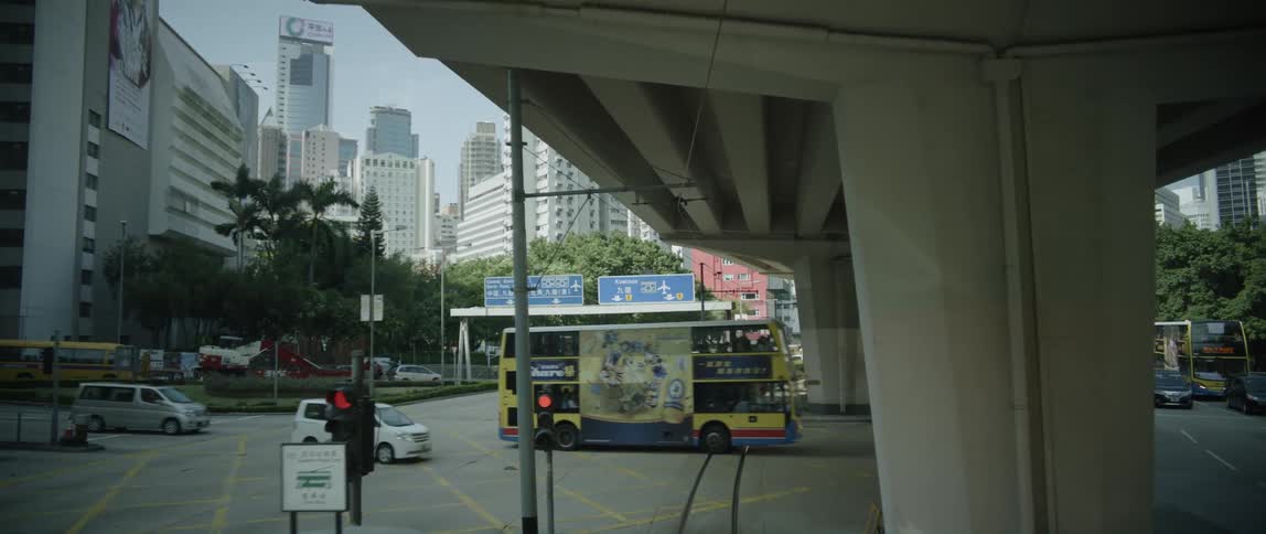 Traffic passes through an intersection beneath an overpass in a metropolis during the day