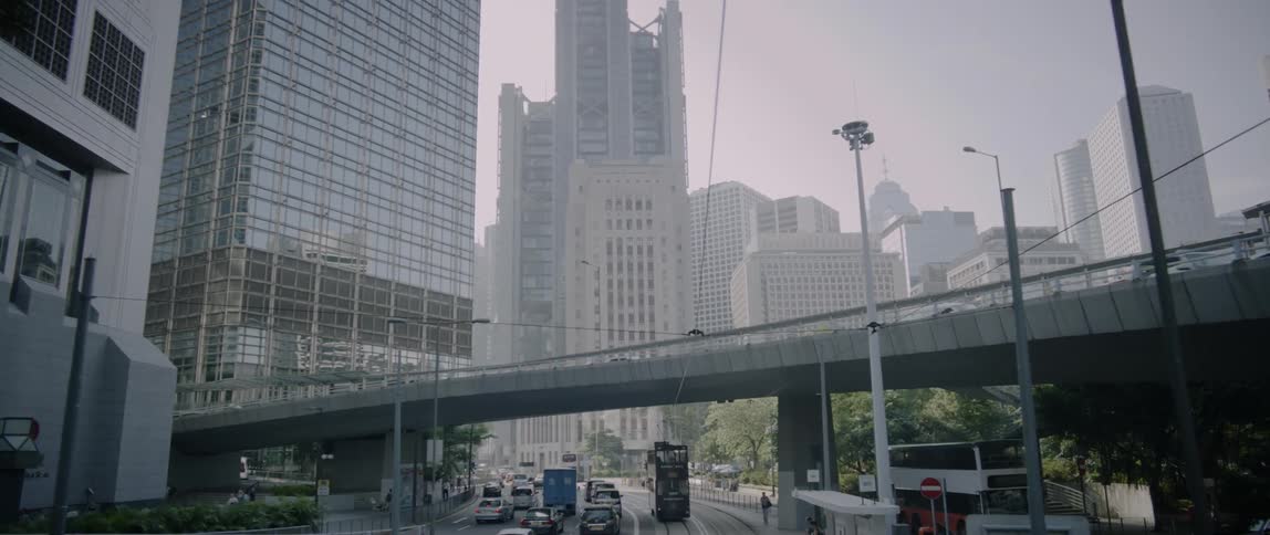 Cars and buses driving down a city street past office buildings